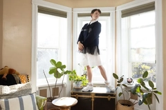 Image young person stands on table in the middle of a bright and fresh room. Looking around admiringly.