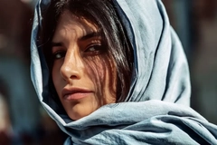 Image young woman with blue cloth draped over her head looks into camera