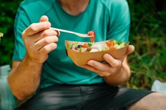 Image man eating salad from paper-based tray