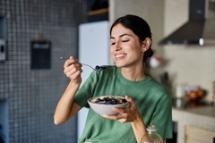 young woman preparing and eating breakfast, drinking juice in the kitchen