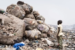 Image A child standing next to a pile of garbage
