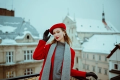 Image a woman stands with a beret and coat and red gloves