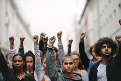 Image young people stand together at a protest with fists in the air