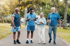 senior man and woman speak with two young men, wearing sports outfit in park