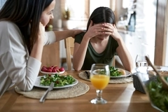 mother supporting her daughter at dining table, mental health and diet concept