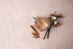 Vanilla and a perfume bottle on a tan table.