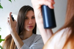 A woman putting dry shampoo in her hair.