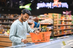 Indian man standing at grocery shop looking into freezer