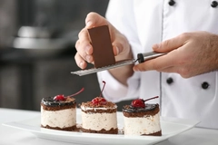 Chef grating chocolate shavings onto chocolate-based desserts.