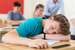 Tired student fell asleep on desk in the class