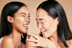 Two women smiling with sunscreen on their cheeks.