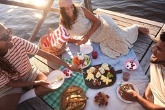 Image two girls and a guy picnic on port above ocean