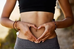 woman holding heart hands over stomach