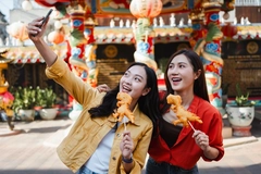 two young asian girls clicking street food photo on mobile