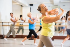 Old lady dancing with other women during group training in studio