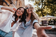 Two women together smiling in the sun.