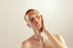Image Man with red hair, looks at camera with hand on face