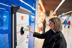Image A person putting a cup into a vending machine