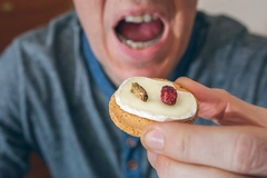 man opening mouth to eat biscuit with cricket insect
