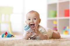 Infant holding milk bottle Infant holding milk bottle