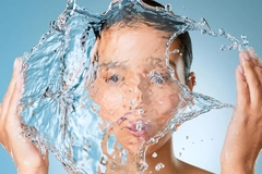Image A woman splashing water onto her face.