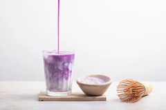 pouring ube flavored syrup into glass of milk