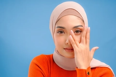 Image A girl in a hijab posing with her hand in front of her face.