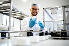 Image A person in a white coat and blue gloves holding a white object