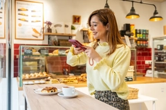 young woman taking photo of bakery item in cafe