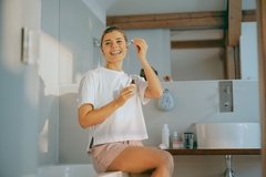 Image woman uses dropper bottle to apply skin care on face