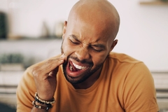 Image man with sensitive touches cheek