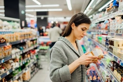 woman reading food label in supermarket