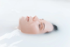 A woman's face coming out of milky water.