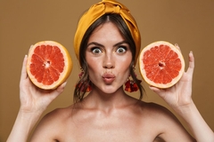 woman holding citrus fruit next to face