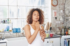 Woman eating chocolate paste in kitchen.