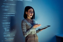 Image A woman holding an iPad with word projections across her face.