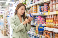 Image woman looking at tuna packaging in supermarket