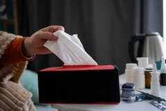 Image A hand grabbing a tissue out of a box.