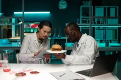 two scientists in lab with a burger sample two scientists analyzing burger with cultivated meat in lab