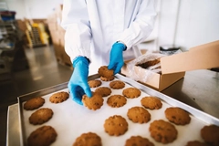 Image A person in gloves putting cookies into a box