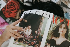 Image A girl holding a magazine with a Gucci advertisement.