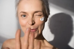Image woman with white hair smiling at camera winking, cream on cheek