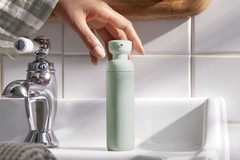 Image A person's hand holding a bottle of toothpaste