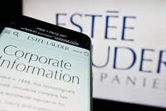 Image A phone reading corporate information in front of Estee Lauder website.