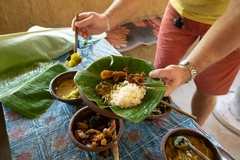 Image man servers food onto banana leaf plate