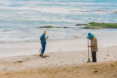 Image two men clean up plastic on a beach