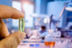 Image hand holding a capsule against the background of a blurred laboratory room.
