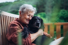 Image Older woman with dog sitting on terrace.
