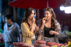 Image Friends eating fruit at vibrant Asian night market