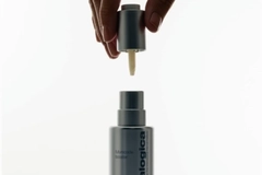 A hand holding a bottle of skin care product